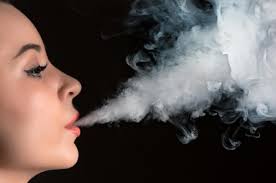 Woman exhaling smoke against a black background